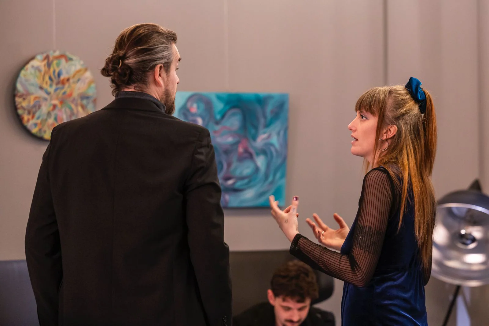 Nina échange avec un visiteur devant ses toiles.
