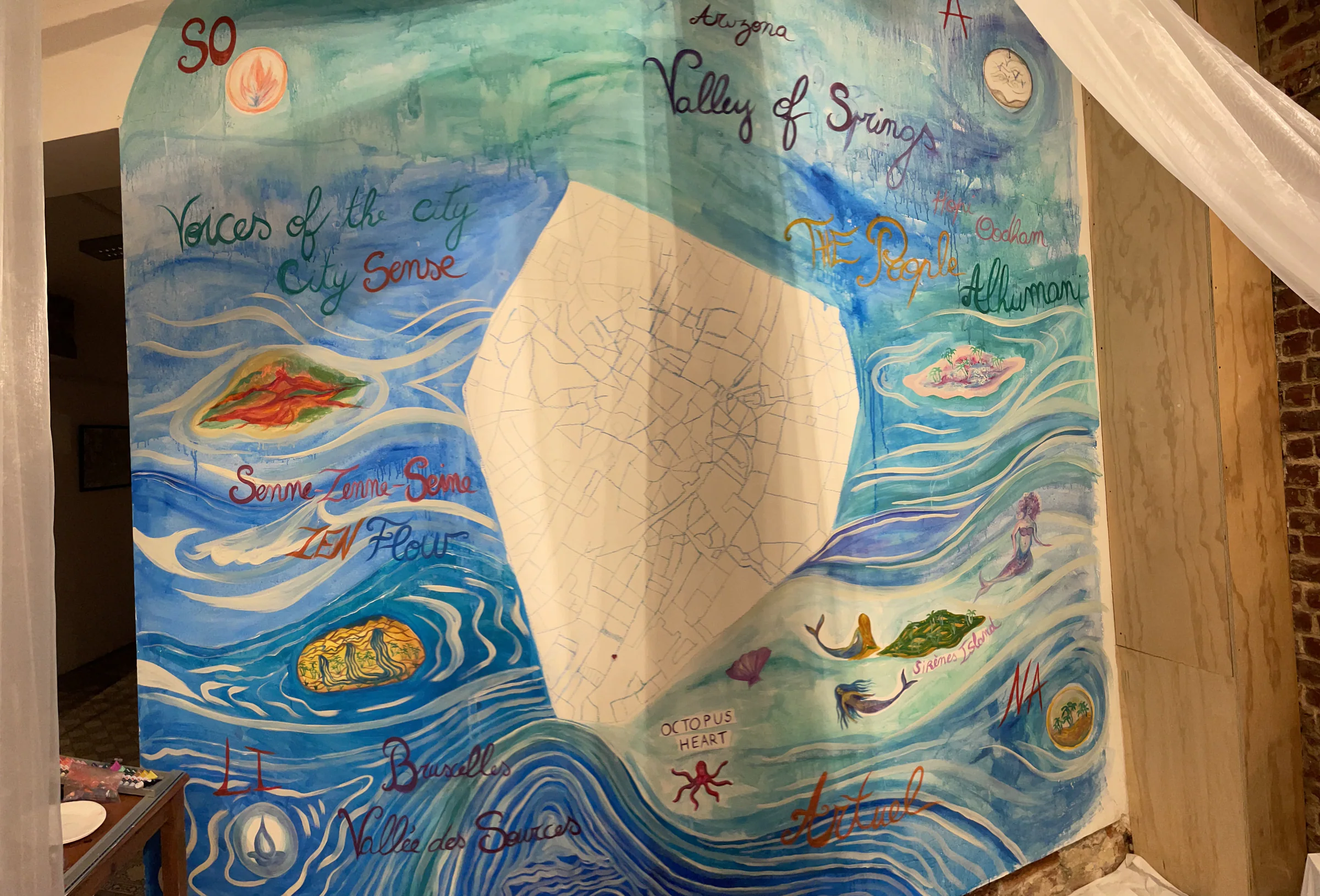 Grande fresque marine peinte sur un mur, avec des poissons, des coquillages et des mots.