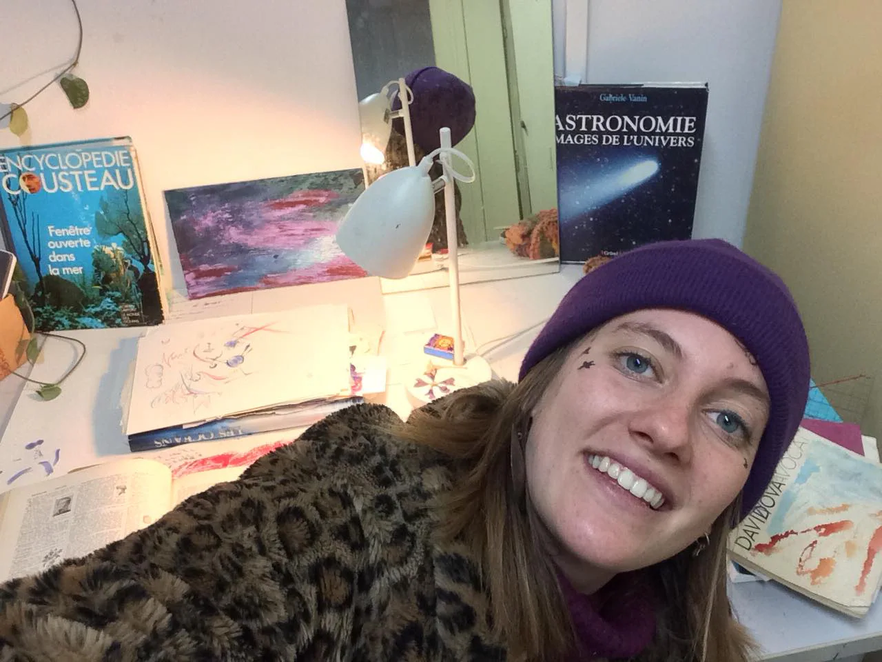 Nina Manon à sa table de travail, entre une encyclopédie Cousteau et un livre d'astronomie.
